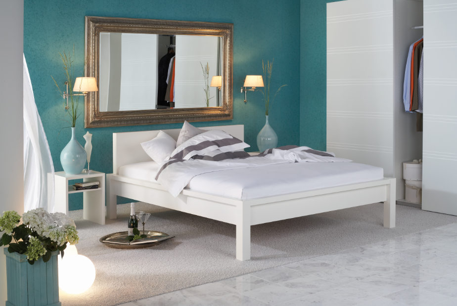 Weißes Bett mit türkisfarbenen Hintergrund